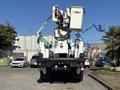 A 2013 International 7500 bucket truck with a white elevated work platform and equipment attached to the boom