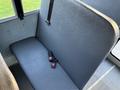 A gray bench seat with a seatbelt in the foreground of a bus interior