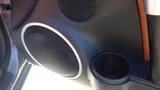 Close-up of the interior of a 2007 Mazda Miata featuring a round speaker and a cup holder