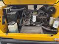 A yellow 2004 Bombardier SW48 engine compartment showing the engine, various hoses, and components including a coolant reservoir and a fuel filter