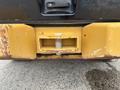 Close-up of the rear hitch attachment of a 2012 Caterpillar 980 featuring a rectangular slot with a bolt visible in the center and worn yellow paint on the bumper