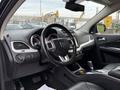 The interior of a 2013 Dodge Journey featuring a black steering wheel with controls a modern dashboard and leather seats