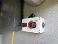 Control panel with a red push button labeled stop and a connector attached to a yellow cable