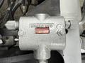 A silver hydraulic valve with the label "BRAND HYD" and a serial number attached. The valve features multiple connection points for hydraulic lines.