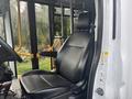A black leather driver's seat inside a 2021 Ford Transit-350 with visible controls and a steering wheel