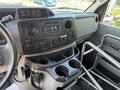 The interior dashboard of a 2013 Ford Econoline showing controls and a compartment with cup holders