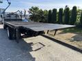 A 2018 Ford F-750 flatbed truck with a black metal surface and a lowered ramp in the rear