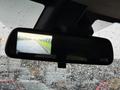 A 2023 GMC Savana's rearview mirror displaying a camera image of the road behind the vehicle