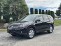 A 2014 Honda CR-V in black parked on the street with its front angled toward the viewer, featuring a sleek design and alloy wheels