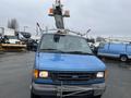 A blue 2006 Ford Econoline van with a raised ladder and orange warning lights on the roof