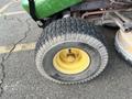 A close-up view of a tire from a 2021 John Deere L Series S lawn mower with a textured black rubber tread and a yellow rim