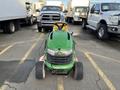 A green 2021 John Deere L Series (S) lawn tractor with a black seat facing forward and large wheels parked on a concrete surface