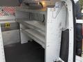The interior of a 2017 Ford Transit Connect featuring metal shelving units with three levels and a tool storage area on the side