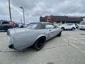 A 1968 Ford Mustang two door convertible in a light gray color with a black soft top and black alloy wheels
