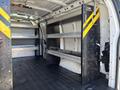 Interior view of a 2019 GMC Savana cargo van featuring metal shelving units and a black rubber floor liner