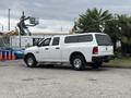 A white 2013 RAM 1500 pickup truck with a camper shell parked on a lot