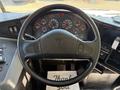 A black steering wheel of a 2013 International CE300 with various gauges and controls visible on the dashboard