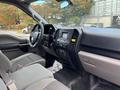 Interior of a 2020 Ford F-150 featuring a gray dashboard and seat with controls on the center console and a steering wheel with various buttons and features