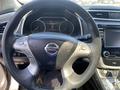 Steering wheel of a 2017 Nissan Murano featuring controls and the brand logo in the center
