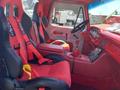 Interior of a 1962 Ford 2WHDR featuring red racing seats with harnesses a black steering wheel and a dashboard with gauges and a digital display