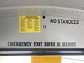 Interior view of a 2006 Thomas Saf-T-Liner HDX bus showing safety signs and labels attached to the ceiling and walls including emergency exit and no standees notices