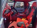 Interior of a 1962 Ford 2WHDR featuring red bucket seats and a black steering wheel with gauges on the dashboard