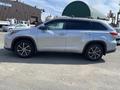 A silver 2018 Toyota Highlander is shown from the side with a sleek design and modern features including alloy wheels and tinted windows