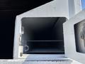 A white storage compartment of a 2019 Freightliner M2 106 truck with an open door showing empty shelves inside