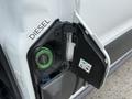 A 2017 Ford Transit van with its fuel door open showing a green diesel fuel cap inside