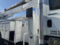 A white 2013 International 7500 truck with a hydraulic lift system and compartments for tools and equipment