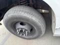 A close-up of a tire from a 2004 Ford F-350 SD showing the tread pattern and wheel rim with five visible lug nuts