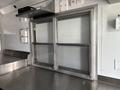A 2020 Freightliner MT45 vehicle interior with sliding glass windows and stainless steel counter surfaces