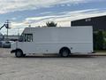 White 2018 Ford Econoline truck with a boxy shape and a sliding side door, parked on a wide concrete area