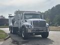 A 2013 International WorkStar truck in white with a large dump bed and multiple lights on the front grille standing on a paved surface