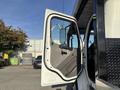A 2022 Freightliner M2 106 truck with its driver's side door open showcasing the interior door panel and window frame