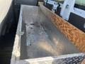A silver metal toolbox with a wooden top sits in the rear of a 2016 Ford F-250 SD truck interior