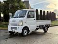 A white 2008 Suzuki Carry compact truck with a flatbed and front cabin design featuring large headlights and a prominent grille