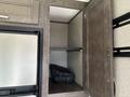 Interior view of a 2021 Jayco Jay Flight with an open storage cabinet displaying a black plastic bin inside