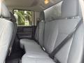 The backseat of a 2016 RAM 1500 featuring gray upholstery and seatbelts with ample legroom and a simple design