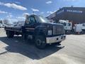 A 1996 GMC Top Kick truck with a flatbed and prominent front grille, featuring a black exterior with orange stripes and large wheels