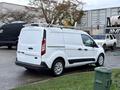 A white 2017 Ford Transit Connect van with a roof rack parked in a lot showcasing its side and rear view