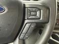 Steering wheel controls of a 2024 Ford E-450 featuring buttons for volume phone and media functions