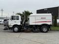 A 2009 UD Trucks UD 3300 street sweeper with a large brush attachment on the front and a white body featuring the Elgin Crosswind logo