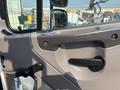 Interior view of a 2010 Freightliner M2 106 door panel featuring a handle a window crank and a side mirror with adjustment controls
