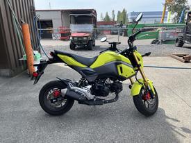 A bright yellow 2018 Honda Grom motorcycle with a compact design, features a black seat, red brake calipers, and sporty styling