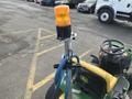 A 2021 John Deere L Series S lawn tractor with an orange flashing beacon light and a blue hose attached near the operator's seat