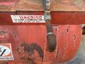 A worn red air compressor with a rusty handle and a warning label indicating it may start at any time