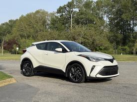 A white 2021 Toyota C-HR with a sleek design sits at an angle showcasing its sporty front grille and distinctive headlights