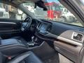 Interior view of a 2018 Toyota Highlander showing black leather seats a central console and dashboard with various controls and a touchscreen display