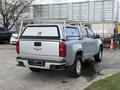 A silver 2018 Chevrolet Colorado with a truck bed cap and a metal ladder rack attached to the bed